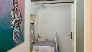 Een wasserette met een wasmachine, een droogrek en een schilderij aan de muur.