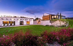 A modern house with a well-maintained lawn and a variety of flowers in the foreground.