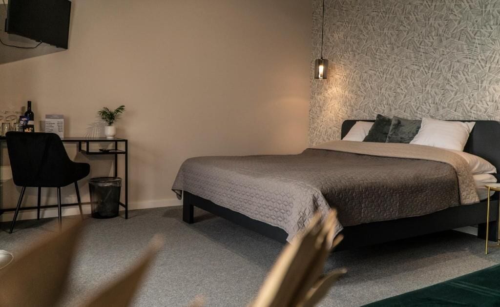 Een slaapkamer met een bed, bureau, stoel en een televisie aan de muur.