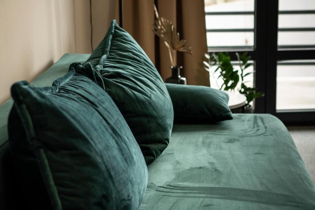 Una cama con ropa de cama verde y un adorno en la mesita de noche.