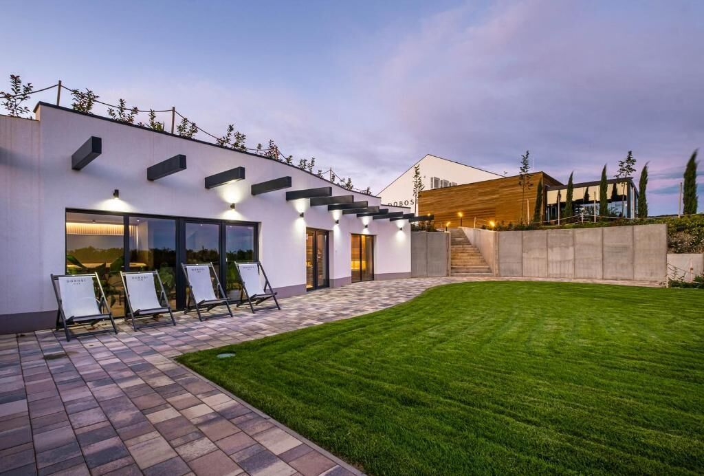 A modern building with a flat roof, large windows, and a well-maintained lawn.