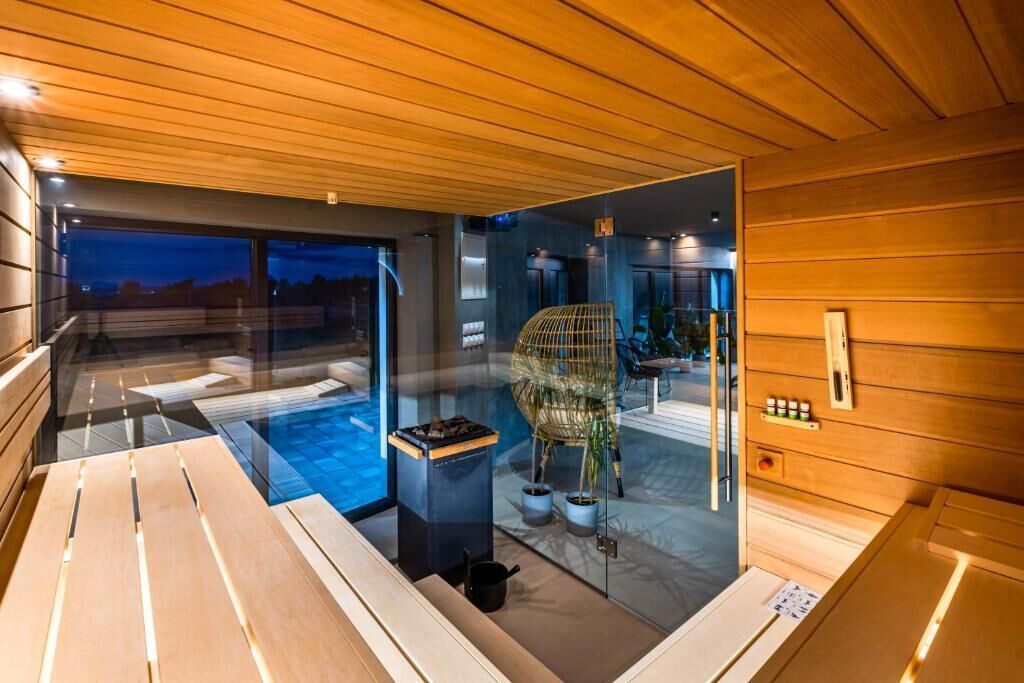 Una sala de sauna con bancos de madera, una pared de vidrio y una silla.