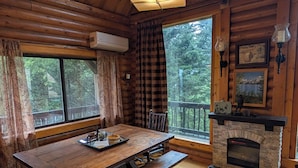 A wooden cabin interior with a dining table, benches, a fireplace, and large windows. - Private Mountain cabin, hot tub, 10 min. to Bozeman  10 min. to Bridger Bowl (Bozeman)
