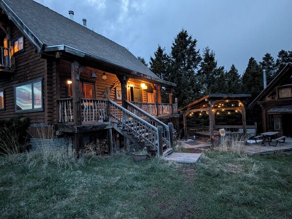 A log cabin with a porch, outdoor seating, and a covered area with string lights.