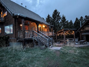 A log cabin with a porch, outdoor seating, and a covered area with string lights.