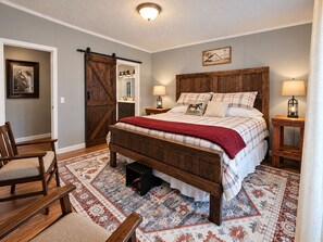 A bedroom with a large bed, a wooden bench, a chair, a rug, and a barn-style door. - 47-Acre Farm Stay Near Bell Buckle & TN Whiskey Trail (Wartrace)