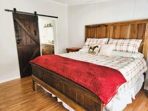 Ein Schlafzimmer mit einem hölzernen Bett, einer roten Decke und einer karierten Tagesdecke.