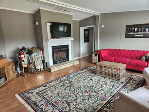 Ein Wohnzimmer mit Kamin, einem roten Sofa, einem Fernseher und einem gemusterten Teppich.