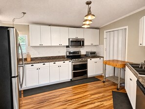 A kitchen with white cabinets, stainless steel appliances, a wooden countertop, and a black refrigerator. - 47-Acre Farm Stay Near Bell Buckle & TN Whiskey Trail (Wartrace)