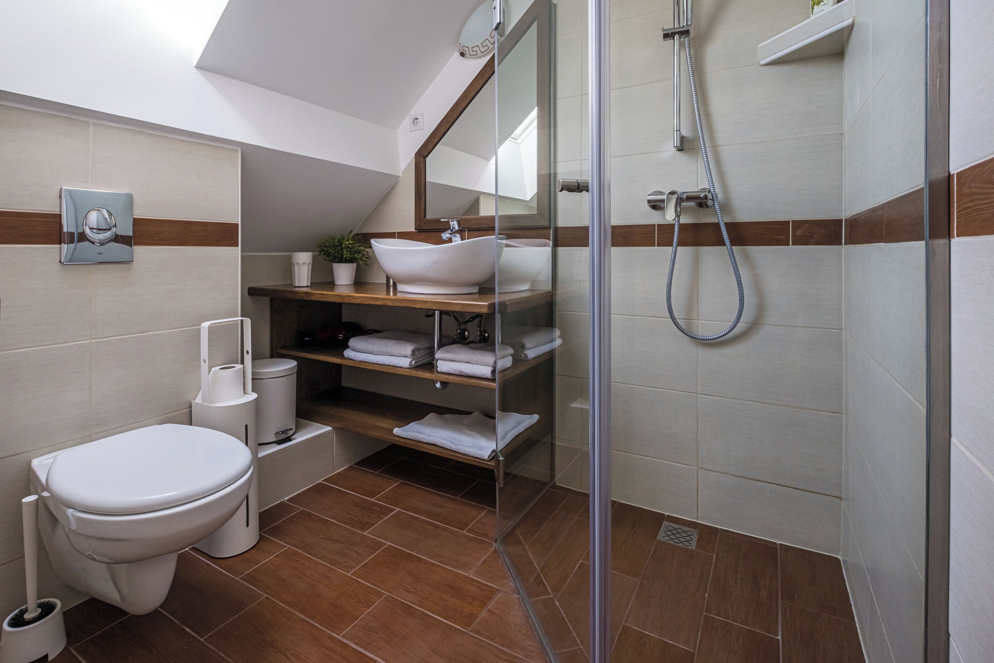 Un baño moderno con inodoro, lavamanos, ducha y cabina de ducha con paredes de vidrio.