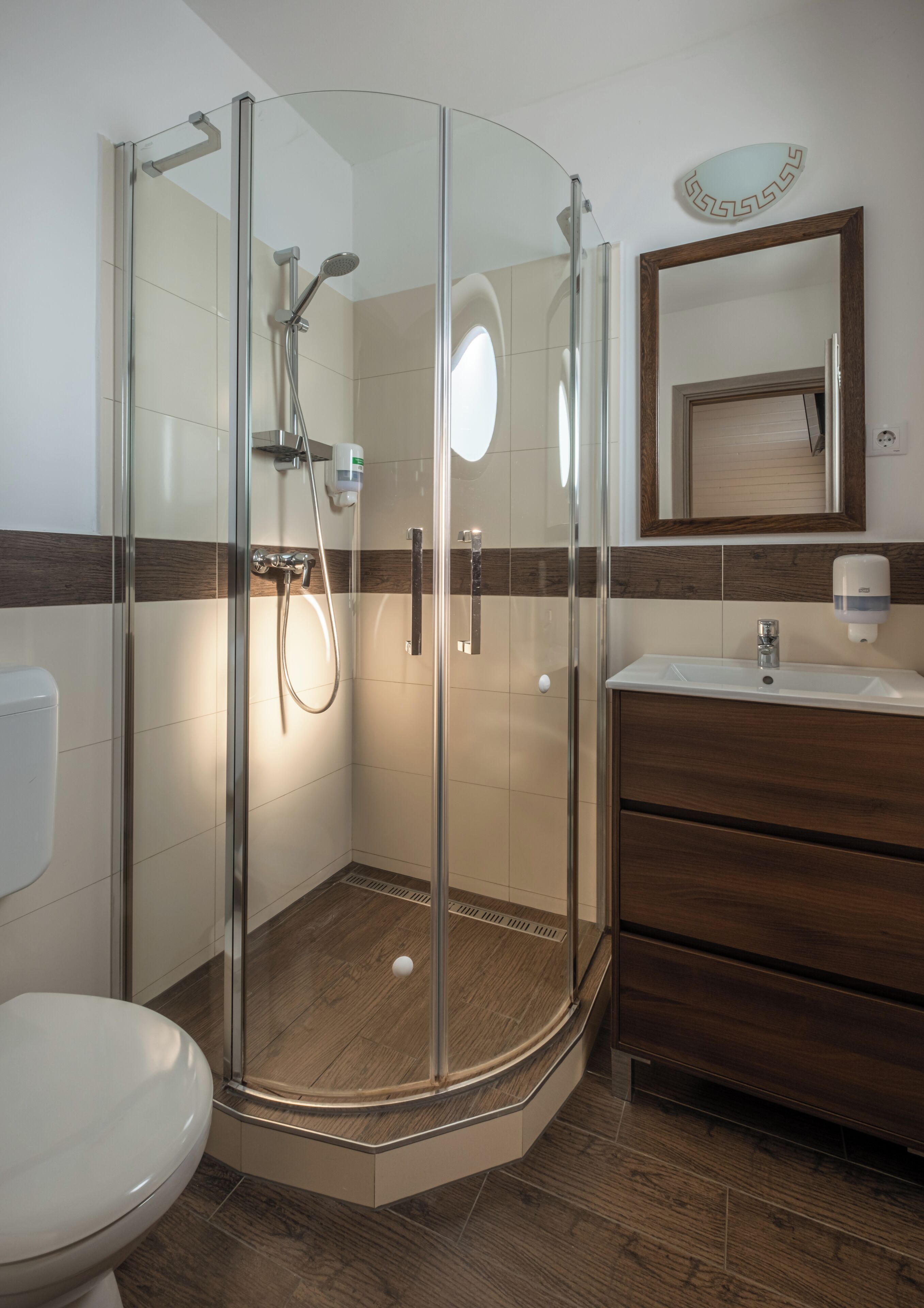 Un baño moderno con ducha envuelta en cristal, tocador de madera y un inodoro.
