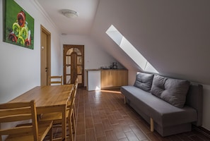 A modern loft apartment with a dining area, kitchenette, and a loft bedroom with a skylight.