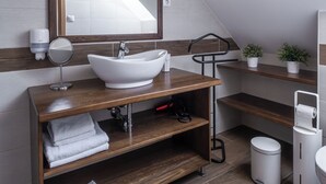 Un baño moderno con un lavamanos independiente, un espejo y un perchero para toallas.