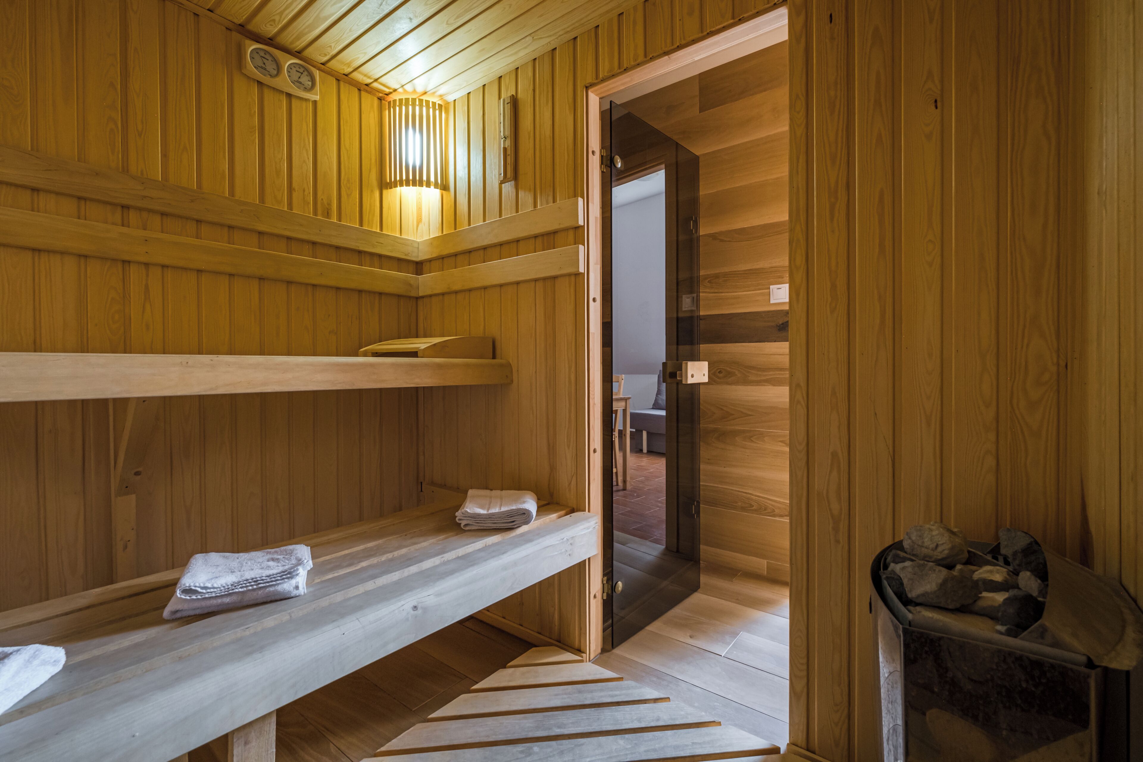 A wooden sauna room with benches and a door leading to another area.