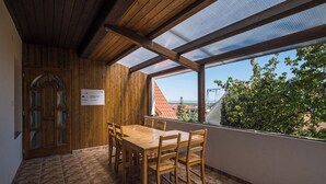 Una habitación con paneles de madera, una mesa, sillas, una puerta con paneles de vidrio y vista por una ventana.