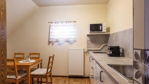 Cocina compacta con mesa, sillas, microondas, cafetera y radiador.