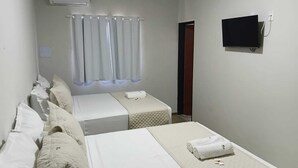 Habitación de hotel con dos camas, televisión y ventana con cortinas.
