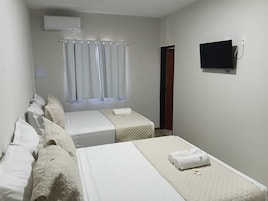 Quarto de hotel com duas camas, televisão e janela com cortinas.