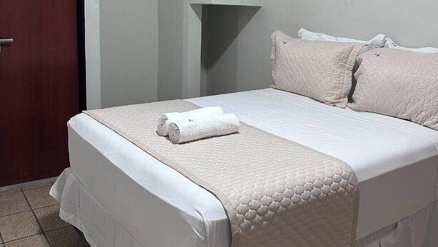 Una habitación de hotel con una cama, una puerta y un accesorio de iluminación.