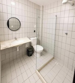 A bathroom with a glass-enclosed shower, a toilet, and a sink with a mirror. - Amalfi Suites Pousada (João Pessoa)