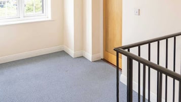 A room with a large window, a door with a number, and a staircase with a railing.