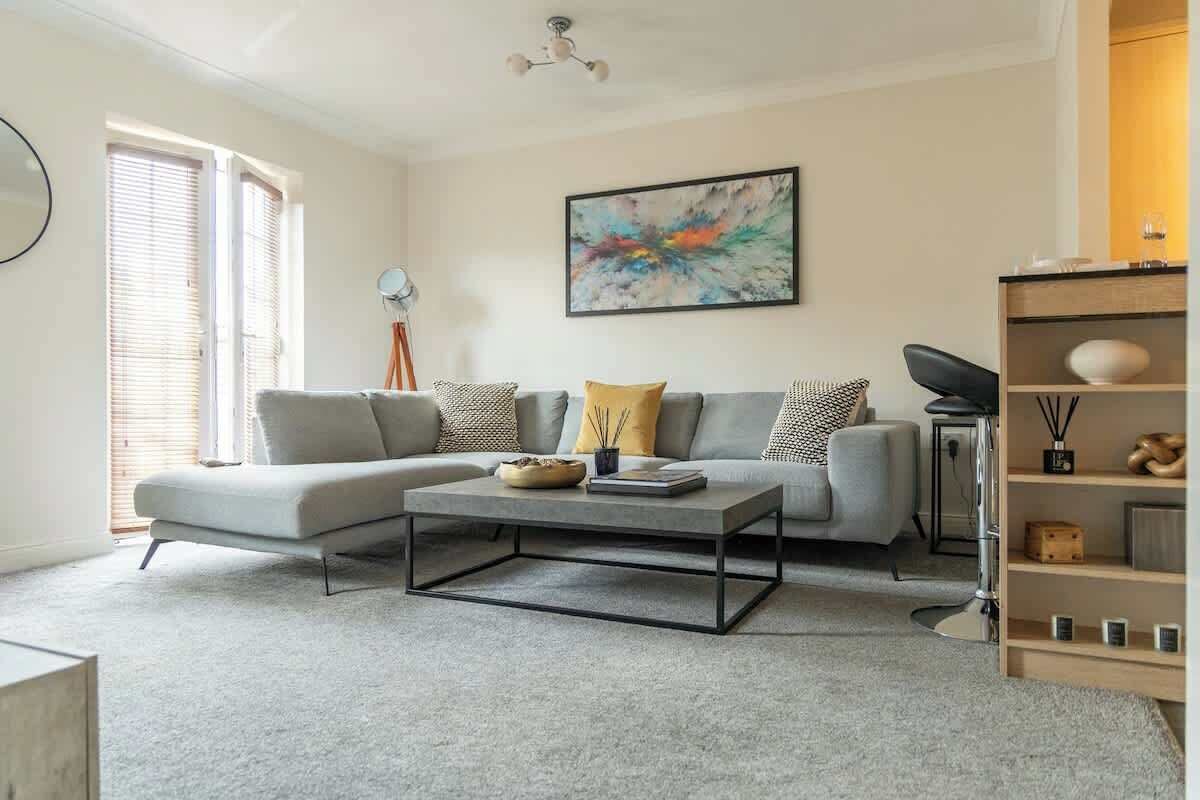 A modern living room with a grey sectional sofa, a coffee table, and a bookshelf.