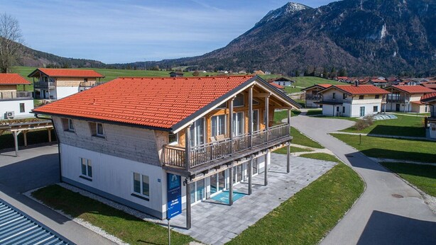 Ein zweistöckiges Gebäude mit rotem Ziegeldach, einem Balkon und einem Poolbereich.