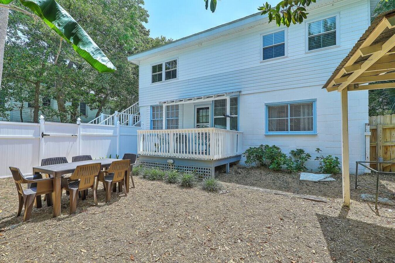 A house with a covered patio, a fenced backyard, and a table with chairs.