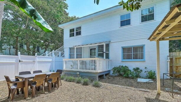 A house with a covered patio, a fenced backyard, and a table with chairs. - “Captain`s Quarters” at Pirates Perch! (Folly Beach)