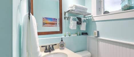 A bathroom with a white sink, a mirror, a towel rack, and a window with a view.