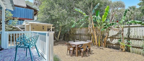 Un patio trasero con terraza, una mesa y sillas, y una valla de madera.