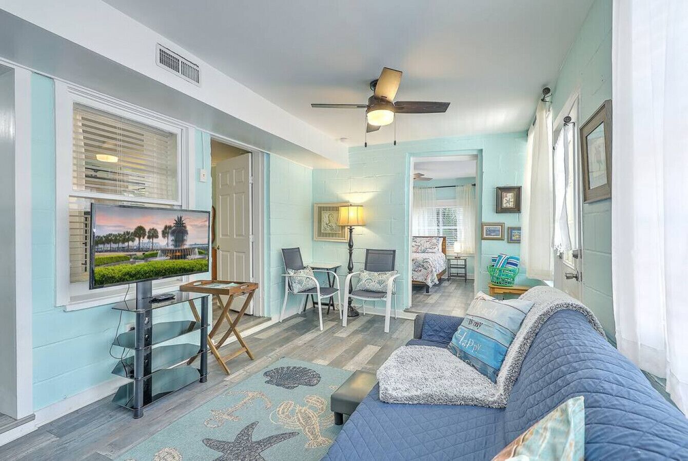 A living room with a television, seating area, and a ceiling fan.