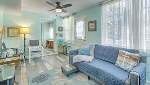 A living room with a blue sofa, a small table, a lamp, and a ceiling fan. - “Captain`s Quarters” at Pirates Perch! (Folly Beach)