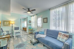 Ein Wohnzimmer mit einem blauen Sofa, einem kleinen Tisch, einer Lampe und einem Deckenventilator.