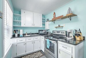 A kitchen with white cabinets, a microwave, a stove, and a coffee maker. - “Captain`s Quarters” at Pirates Perch! (Folly Beach)