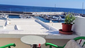 Eine Terrasse mit Tisch und Stühlen, mit Blick auf einen Yachthafen und eine Anlegestelle.