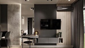 A modern living room with a flat-screen TV mounted on a wall, a dining table with chairs, and a fireplace. - A comfortable apartment in the center of Łódź (Lodz)