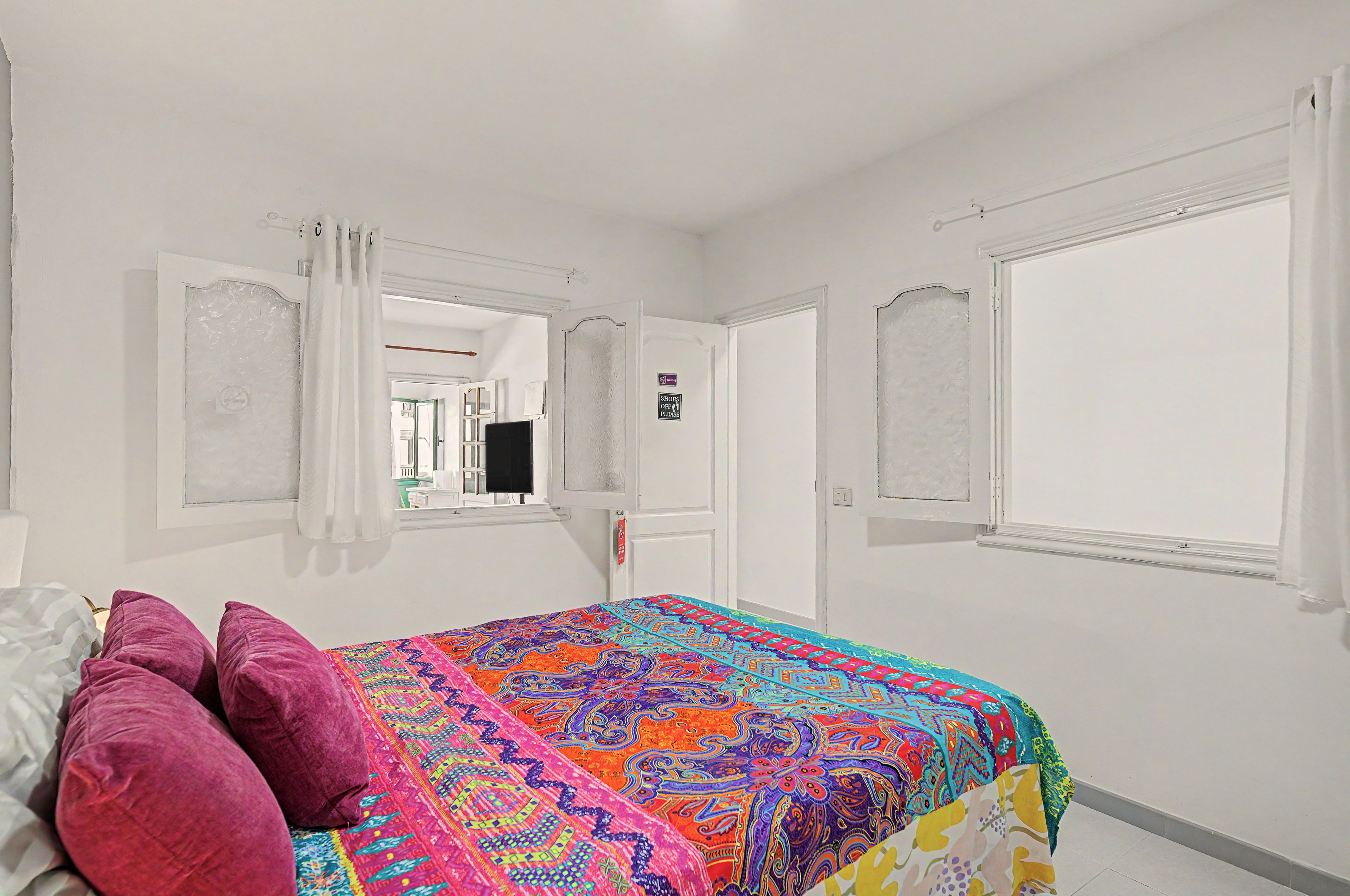 A bedroom with a bed, pillows, a window, and a door.