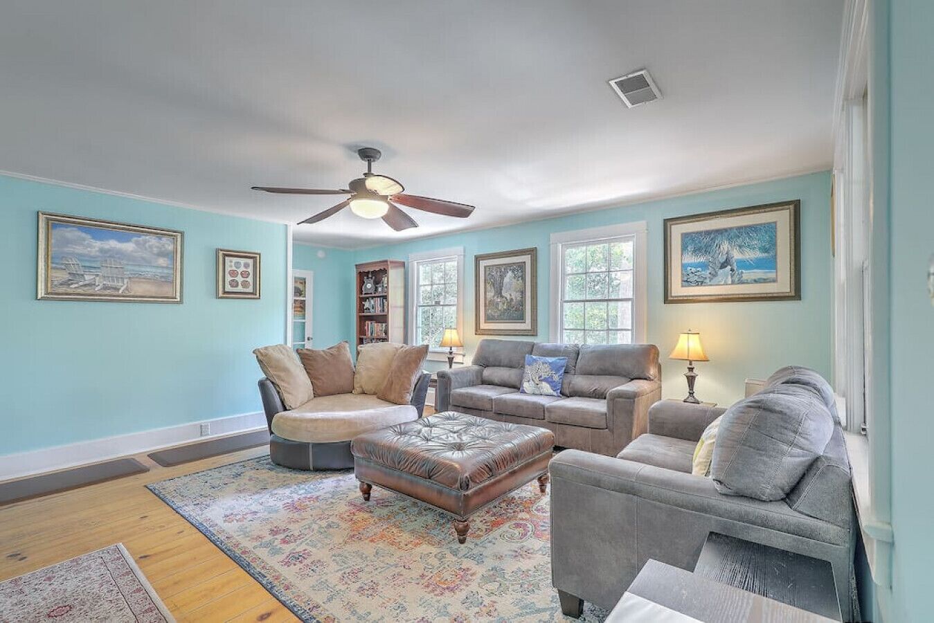 A living room with a ceiling fan, a fireplace, and a large window.