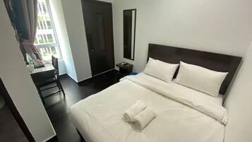 Una habitación de hotel con cama, escritorio, silla, armario y espejo.