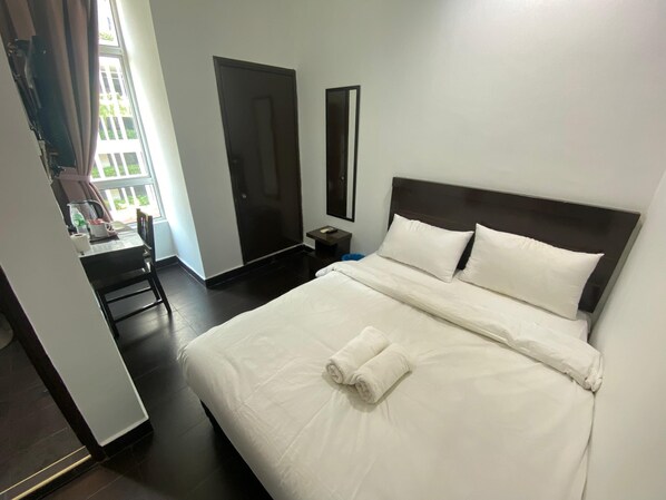 Une chambre d’hôtel comprenant un lit, un bureau, une chaise, une armoire et un miroir.