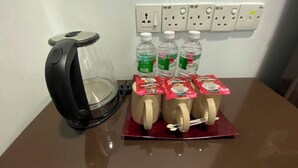 Una cafetera, un dispensador de agua y una bandeja con cápsulas de café y botellas sobre una mesa.