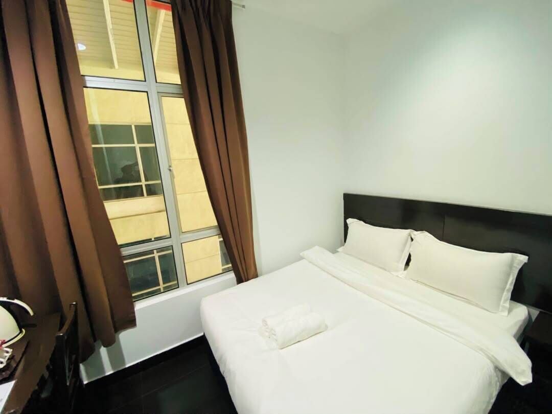 A hotel room with a bed, a window with curtains, and a headboard.