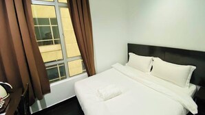 Una habitación de hotel con cama, ventana con cortinas y cabecero.