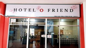 Entrada de un hotel con un cartel que dice 'HOTEL O FRIEND' y un número de contacto.