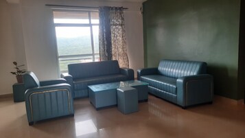 Una sala de estar con un juego de sofá, una mesa de centro y vistas a través de una ventana.
