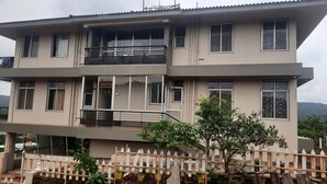 A multi-story building with a reception area, balconies, and a view of the surrounding landscape. - Bison Resort Amboli (Amboli)