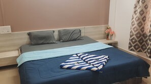 A bed with a blue and white striped pillow, a grey pillow, and a grey blanket.