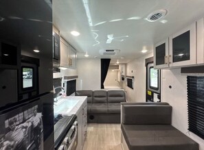 A compact RV interior with a kitchenette, a seating area, and a window. - New RV camper in great nature,spring valley (Hamden)