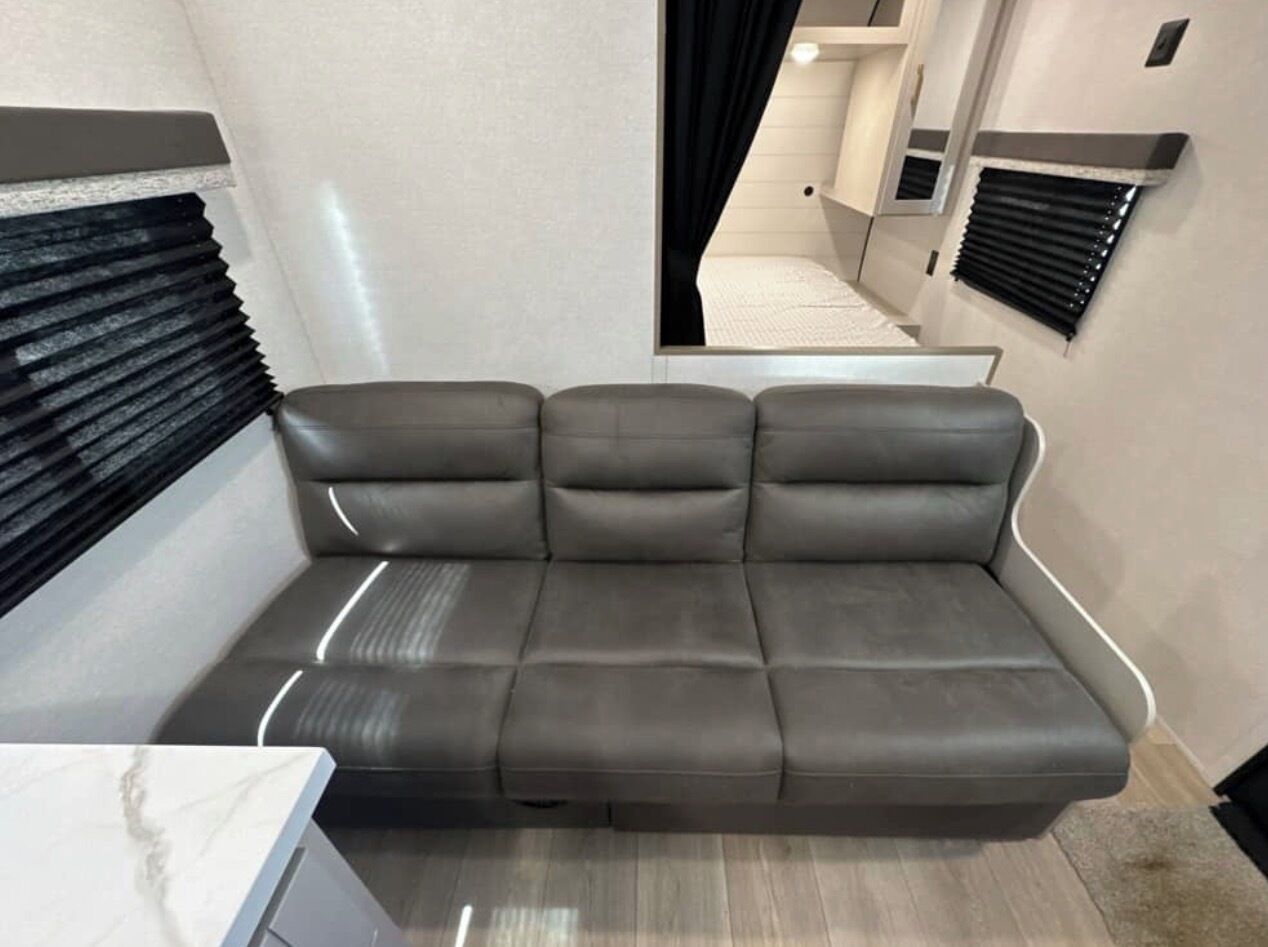 A modern interior with a grey sofa, a marble countertop, and a window with blinds.